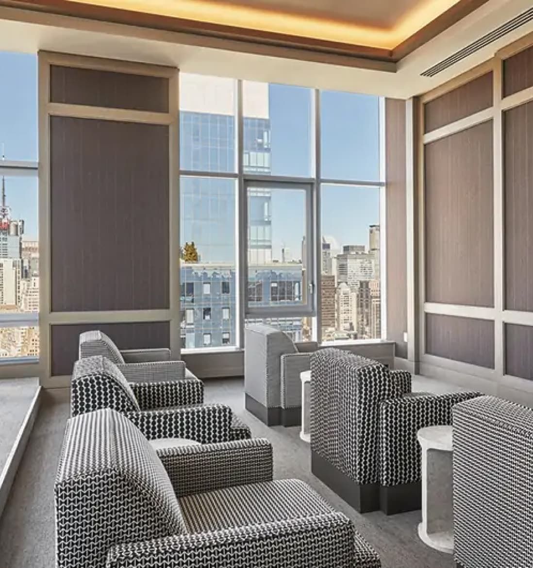 A spacious natural light-filled lounge at EOS featuring chairs and tables arranged in front of large windows, allowing natural light to fill the space.