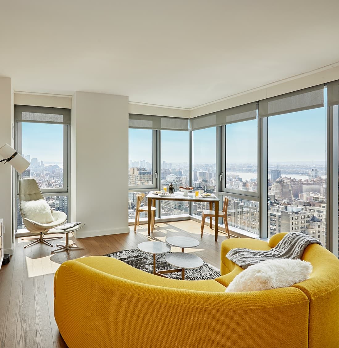 A bright living room featuring yellow furniture and expansive windows that allow natural light to fill the space.