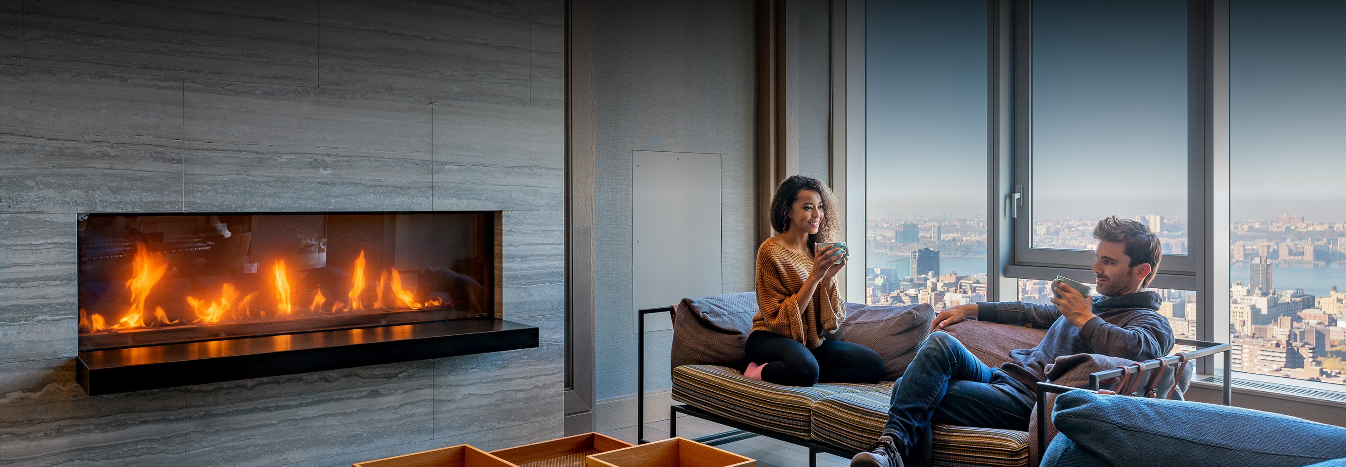 A couple enjoys a cozy moment together in a living room, seated near a warm, inviting fireplace.