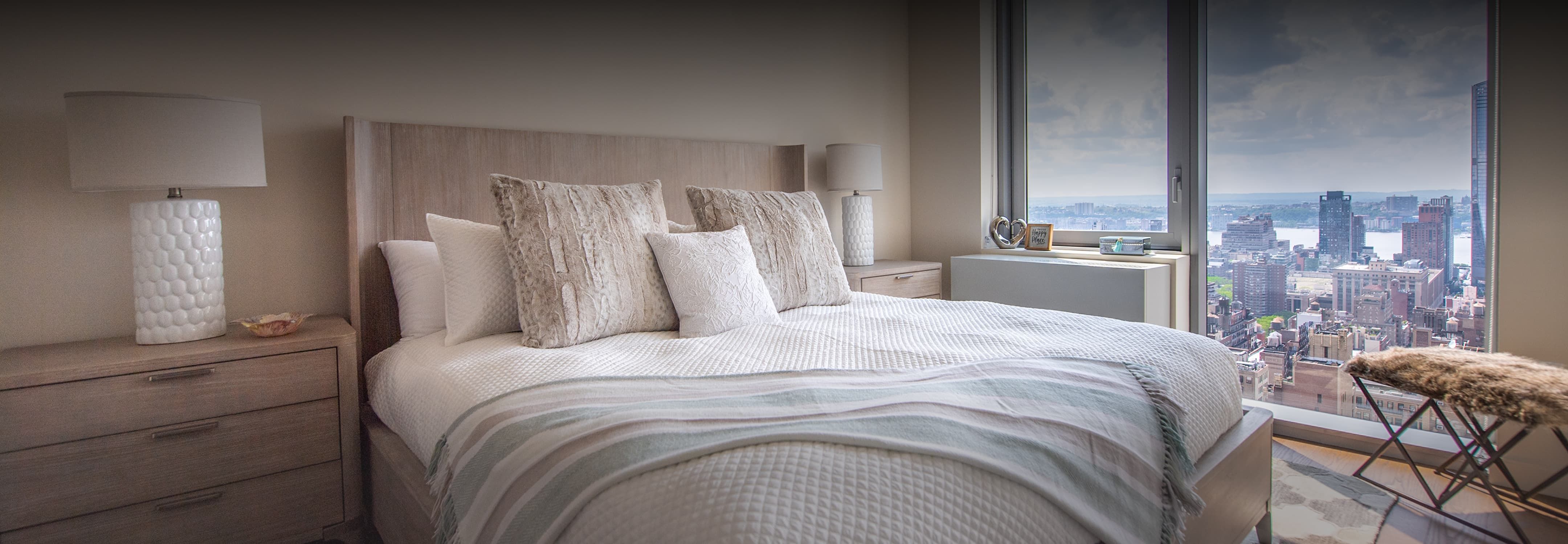 A spacious bedroom featuring a large window that offers a panoramic view of the city skyline.