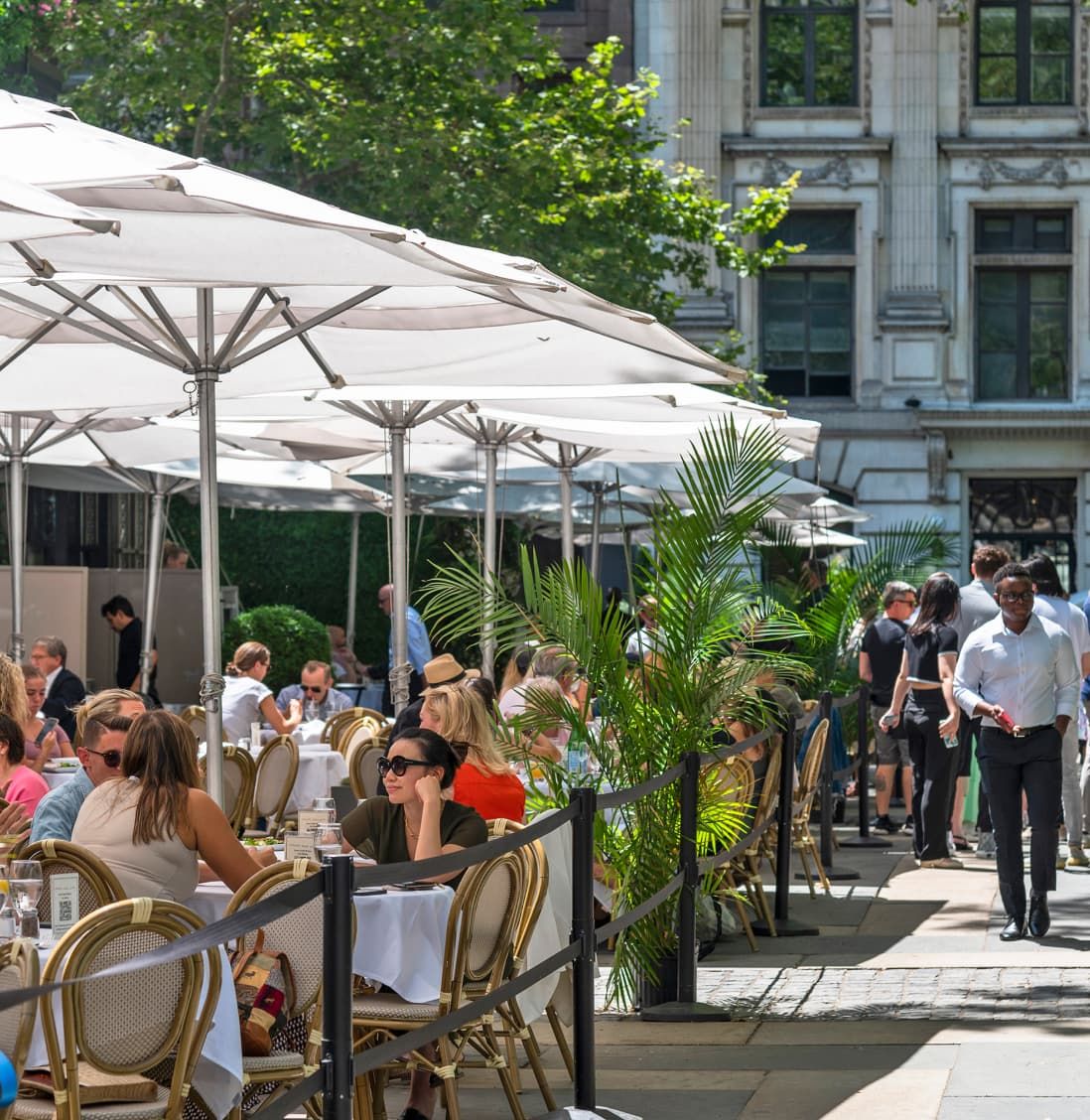 A row of white umbrellas lined up on a sidewalk, providing shade and a serene atmosphere in an urban setting.