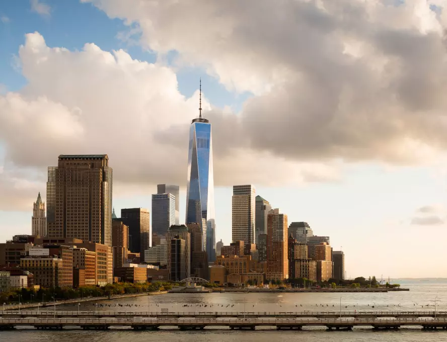 A panoramic view of the New York City skyline, showcasing its iconic skyscrapers against a clear blue sky.